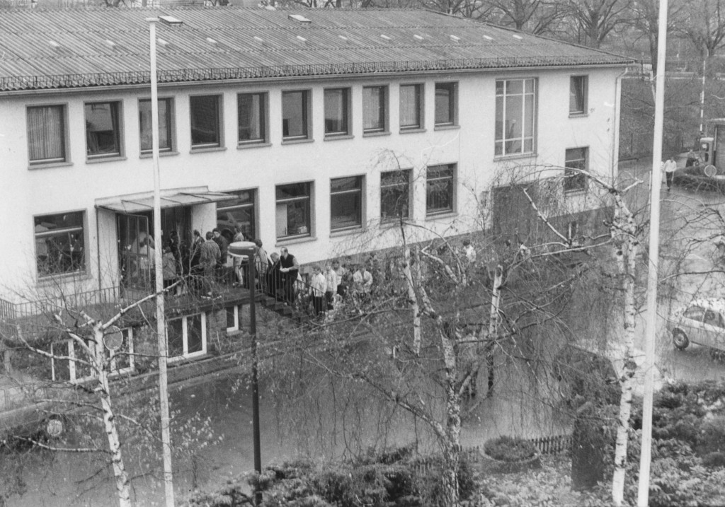Bewohner des Notaufnahmelagers Gießen vor dem Eingang in den Speisesaal Mitte der 80er Jahre. Aufnahme der Stasi. Quelle: Bundesarchiv, BArch MfS HA VII 6273